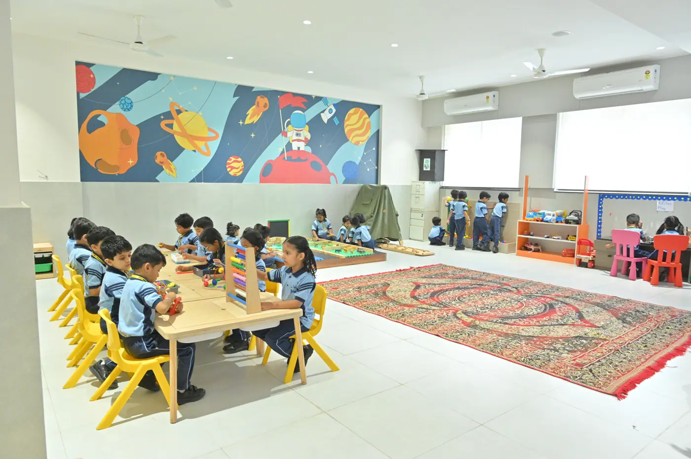 Pre-primary children at activity tables in a bright play room